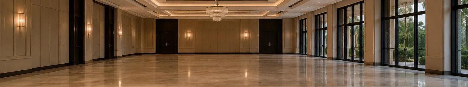 Empty marble ballroom with tall windows and a crystal chandelier, seen from across the polished floor.